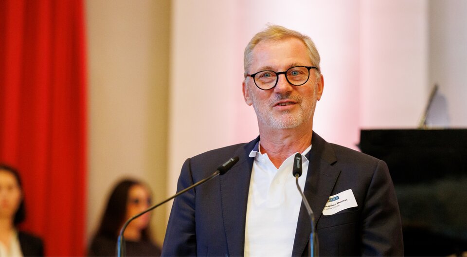Thomas Dietziker parle à un pupitre équipé de deux microphones.